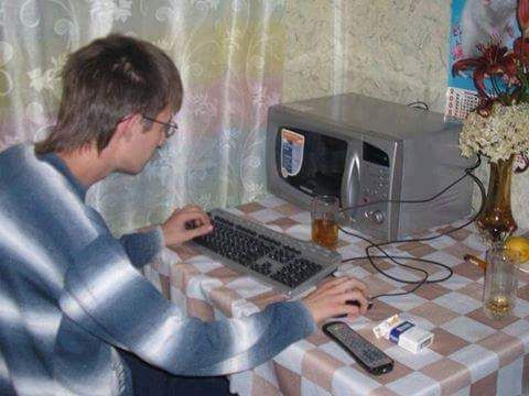 A person using a keyboard and mouse in front of a microwave as if it were a computer.